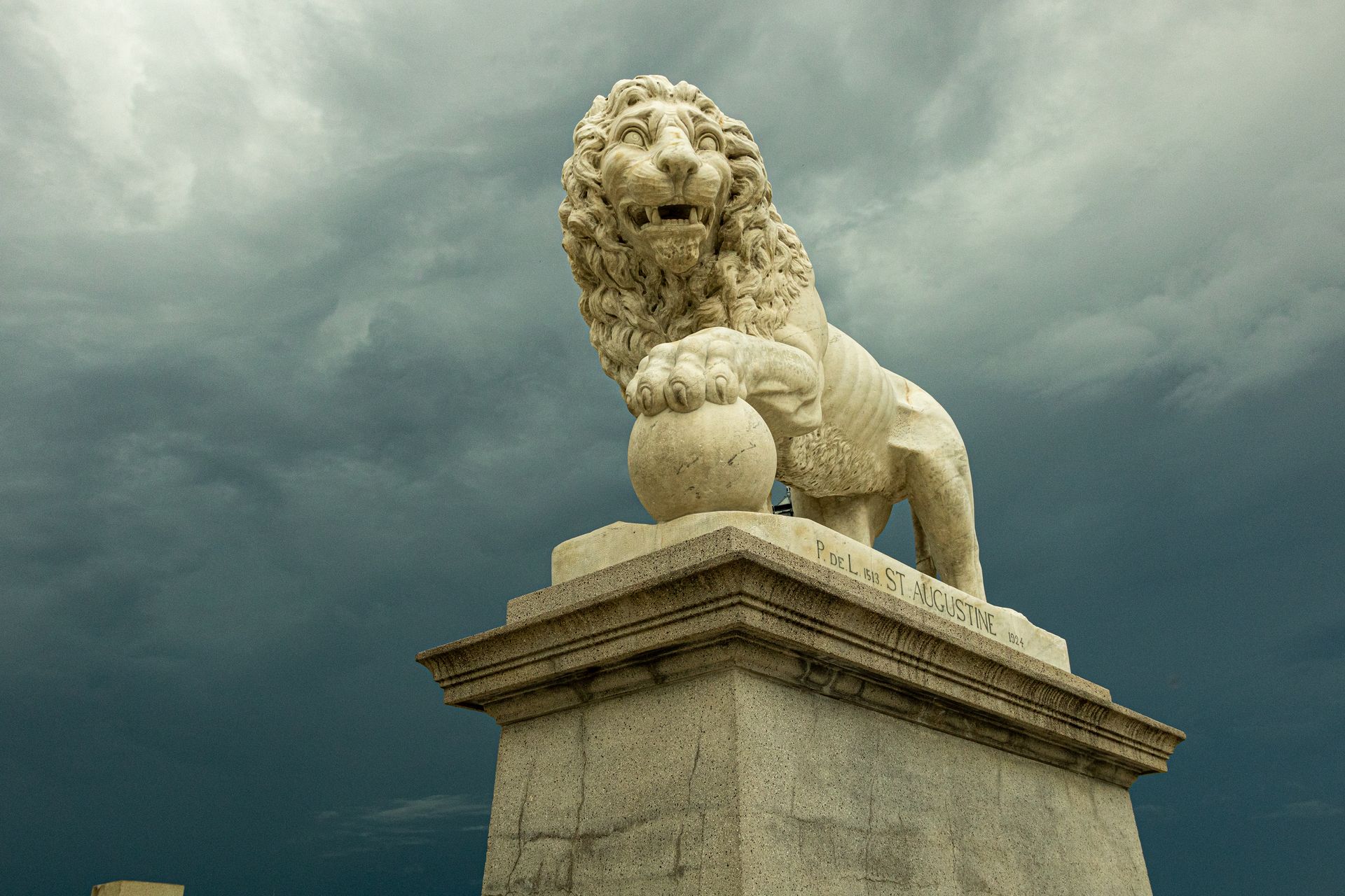 A statue of a lion sitting on top of a stone pillar