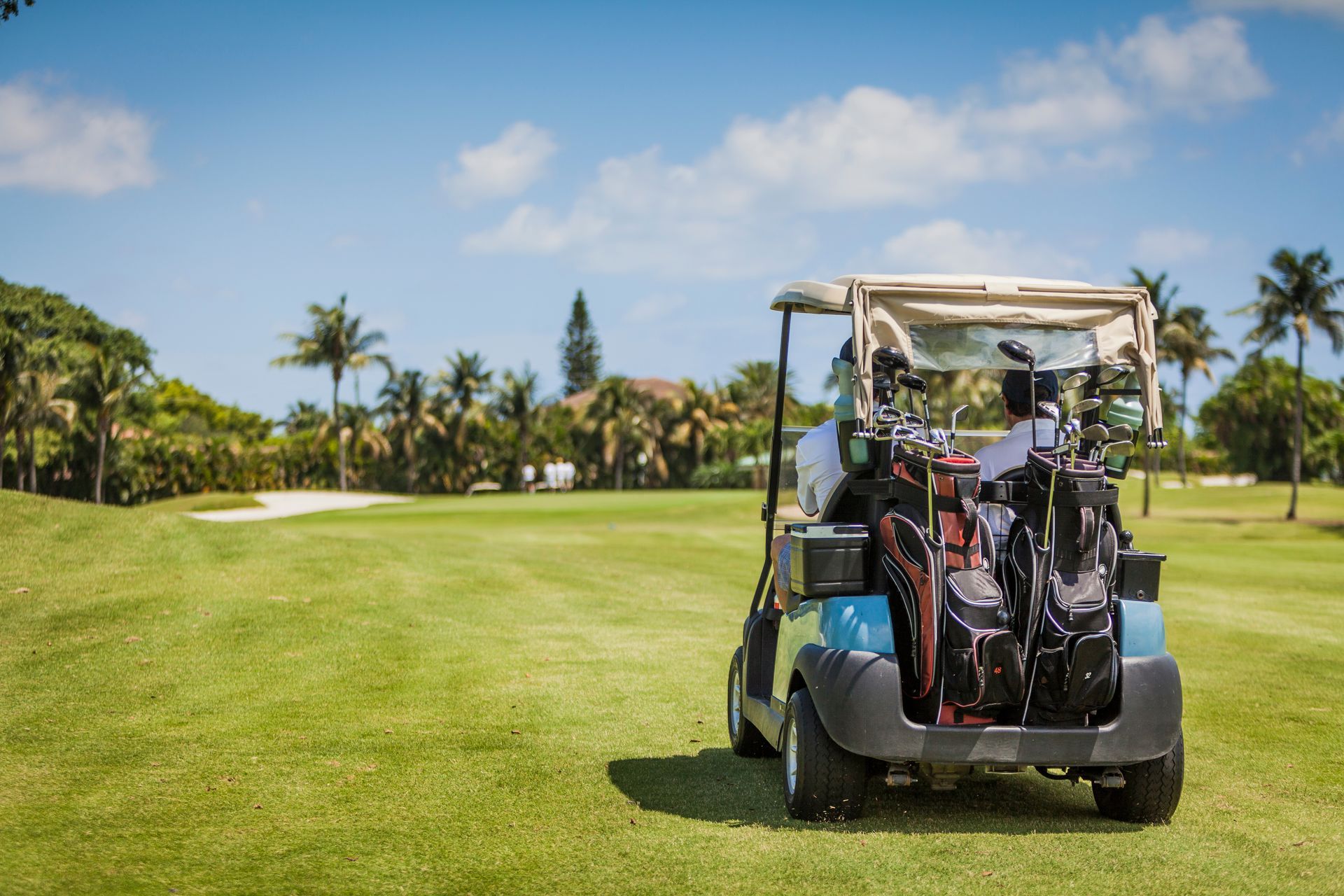 A golf cart is parked on the grass on a golf course.