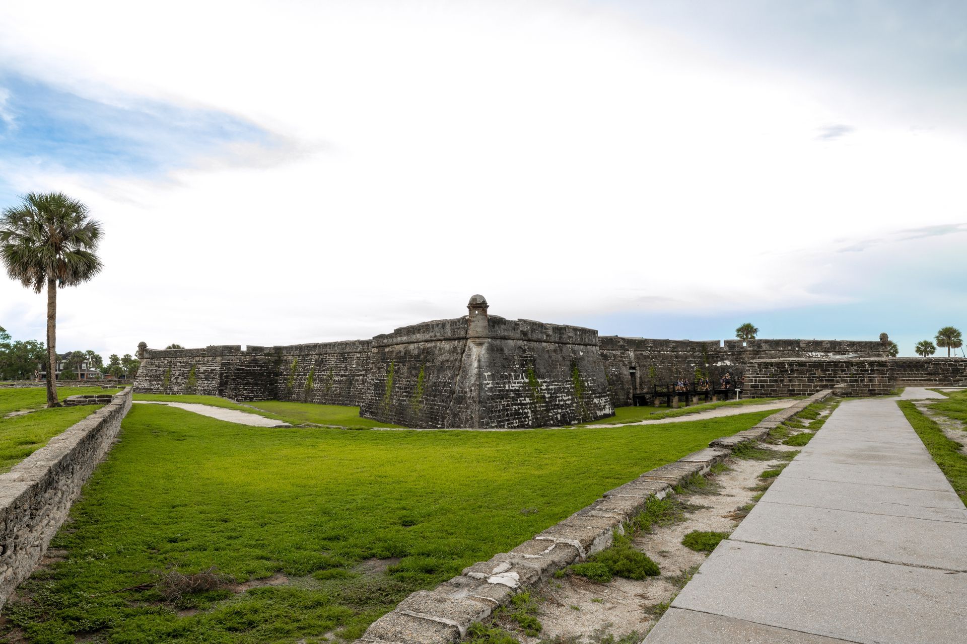 There is a large stone wall in the middle of a grassy field.