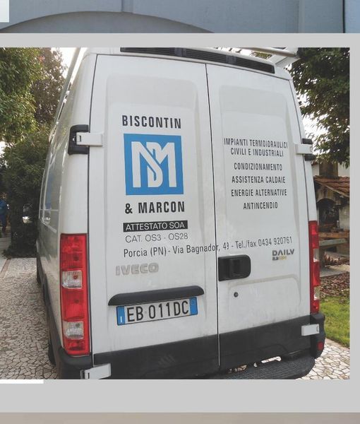 Furgone bianco parcheggiato all'interno di un garage, vista laterale con i loghi aziendali sulla portiera.