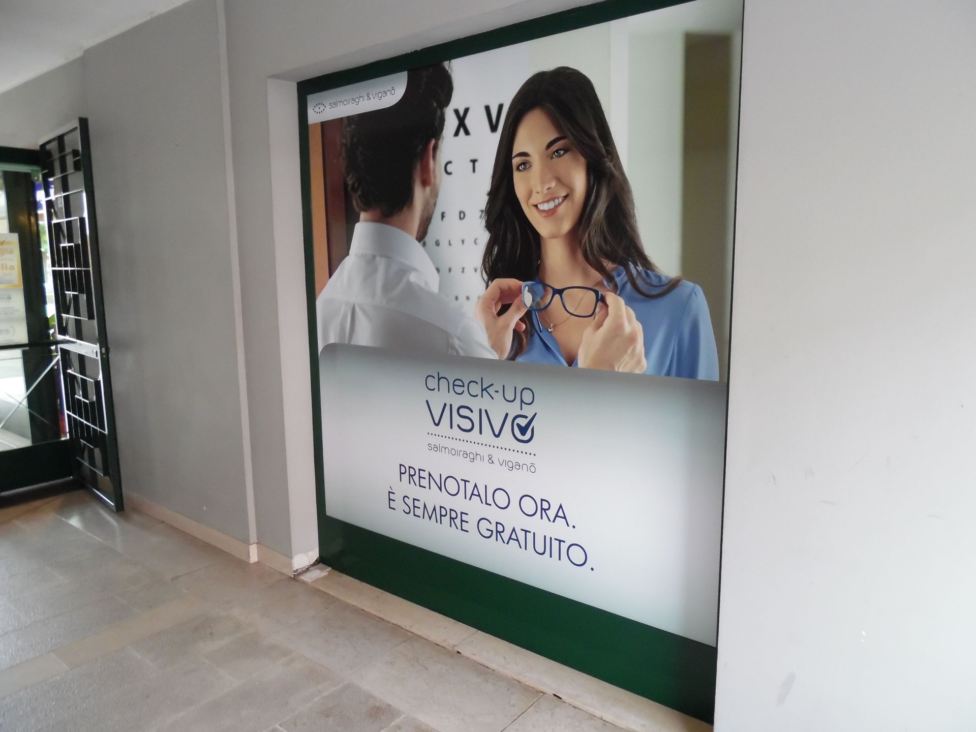 Poster di una clinica dentistica che mostra un paziente sorridente e il dentista con testo in portoghese su una parete bianca.