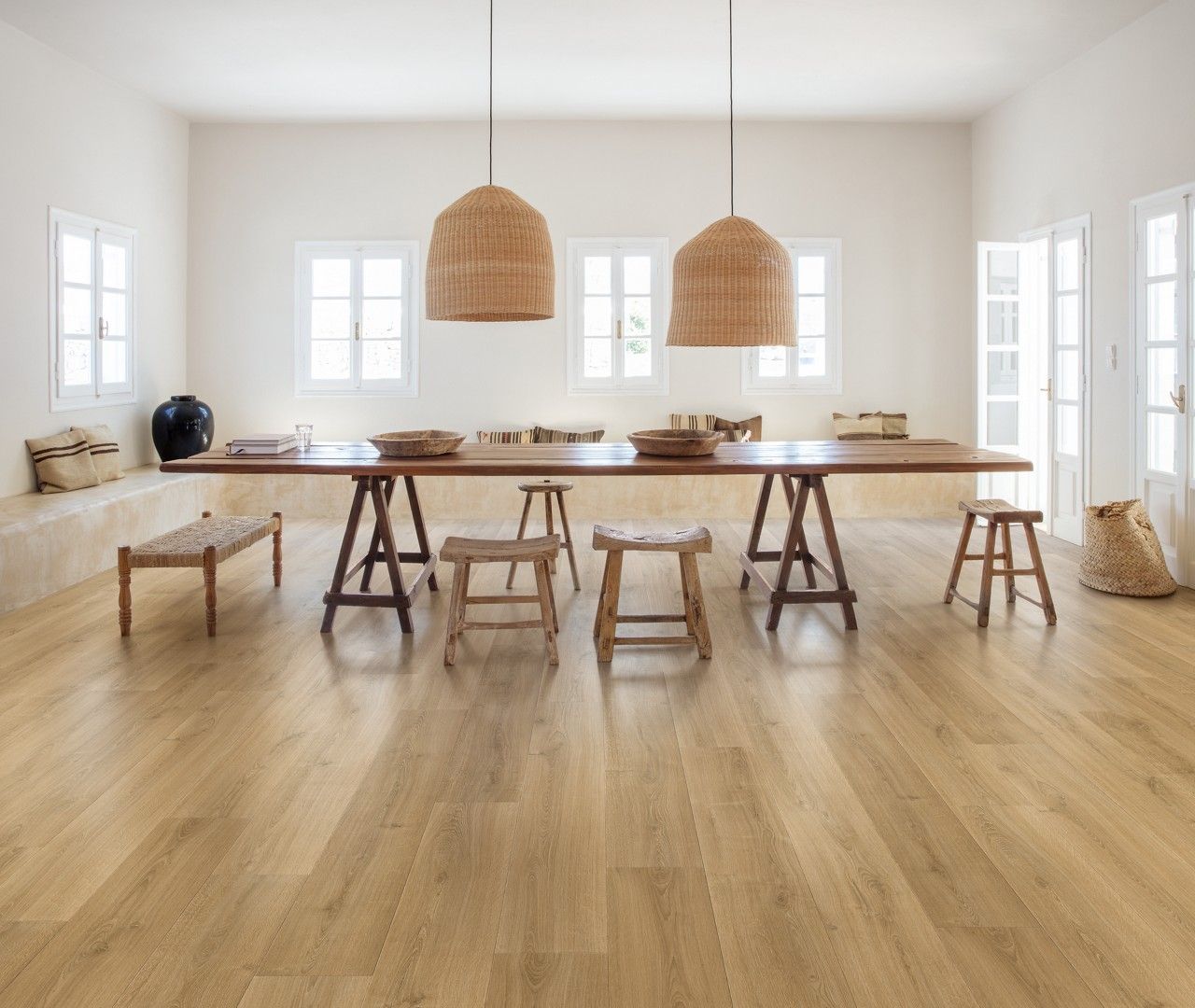 Dining room with long wooden table, wicker lamps, and light wood flooring.
