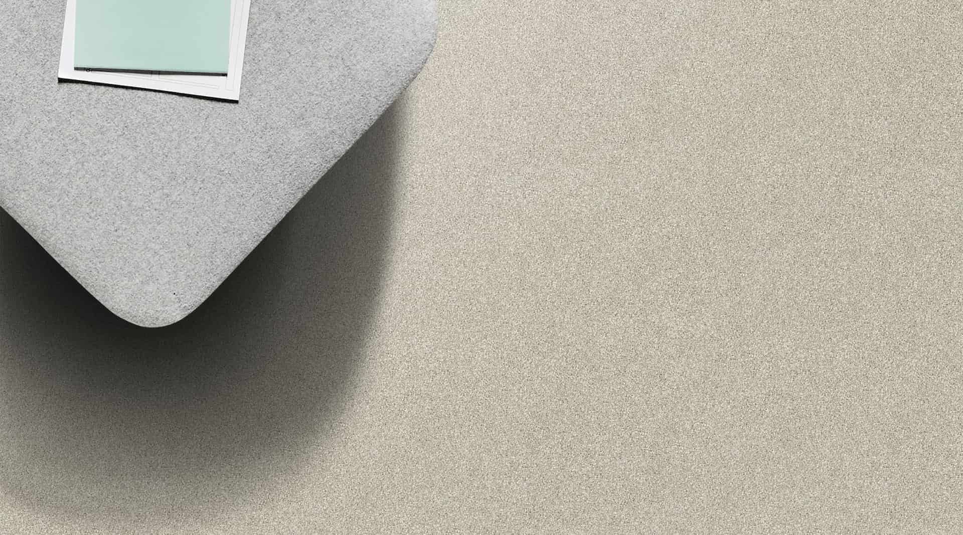 Top-down view of a light gray sofa corner with a photo on top, on a light beige carpet.