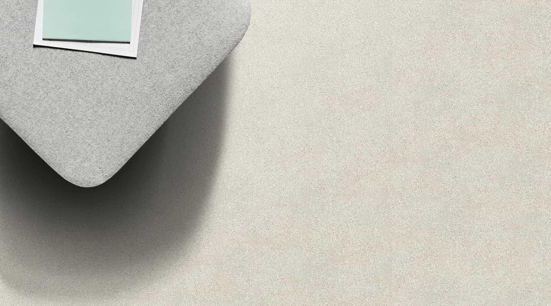Gray corner of a pillow with a light green card on a textured, light beige surface.