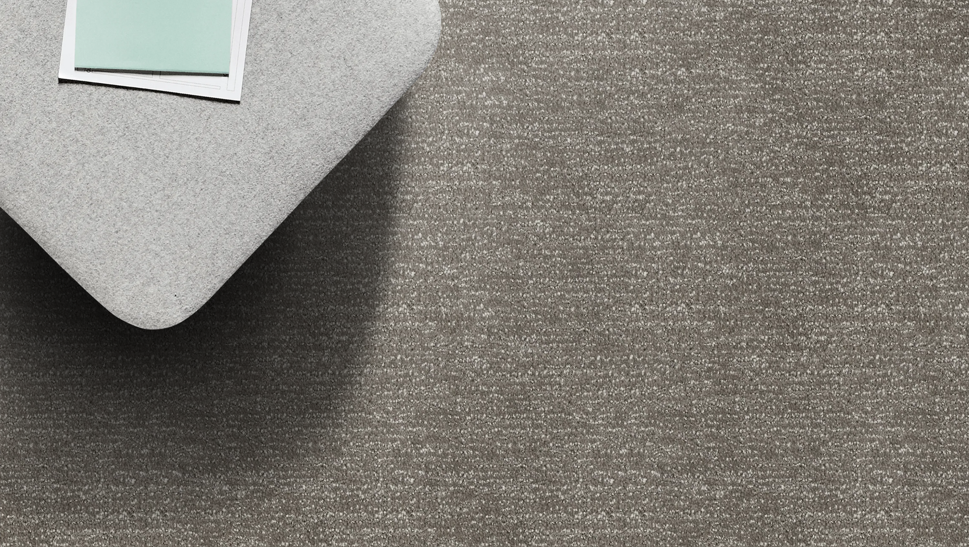Light grey fabric, angled to reveal texture, with a teal and white card on top.