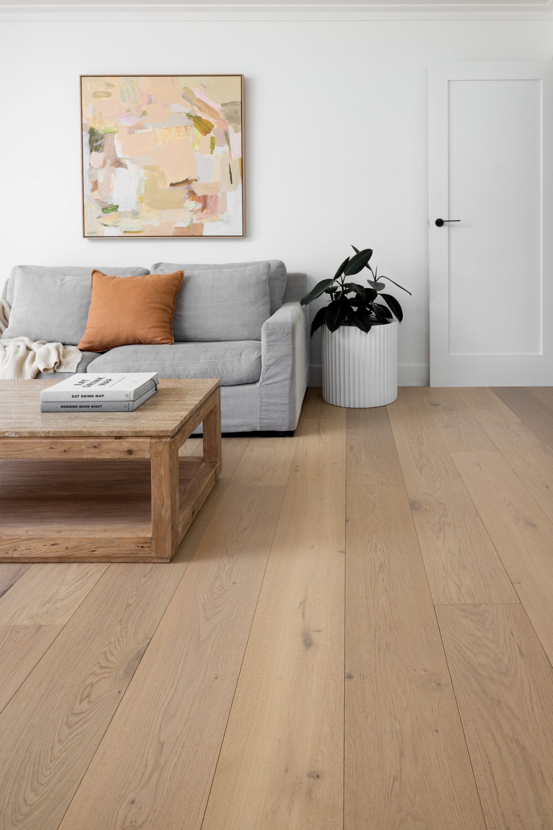 Living room with gray sofa, wooden coffee table, art, and light wood flooring.