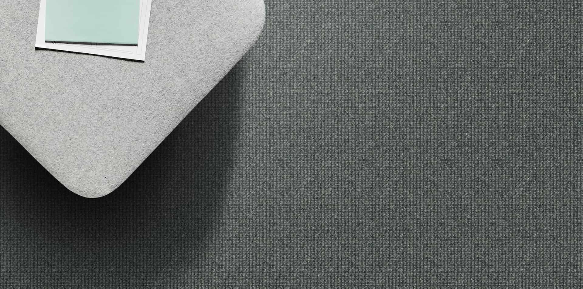 Gray textured surface with a light gray curved object in the upper left corner and a small white and blue rectangle.