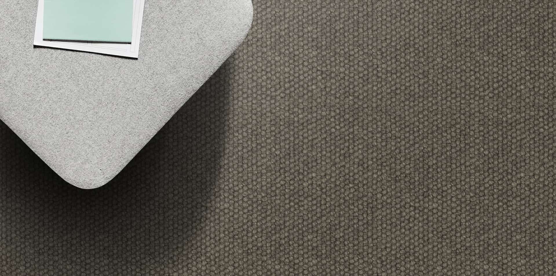 A light gray, curved surface with paper and a piece of paper on top, rests on a dark gray, textured surface.
