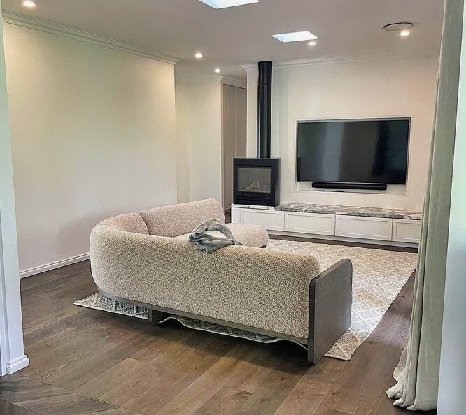 A Living Room with A Couch, Television, and Fireplace — Tony Di Milia Flooring in Unanderra, NSW
