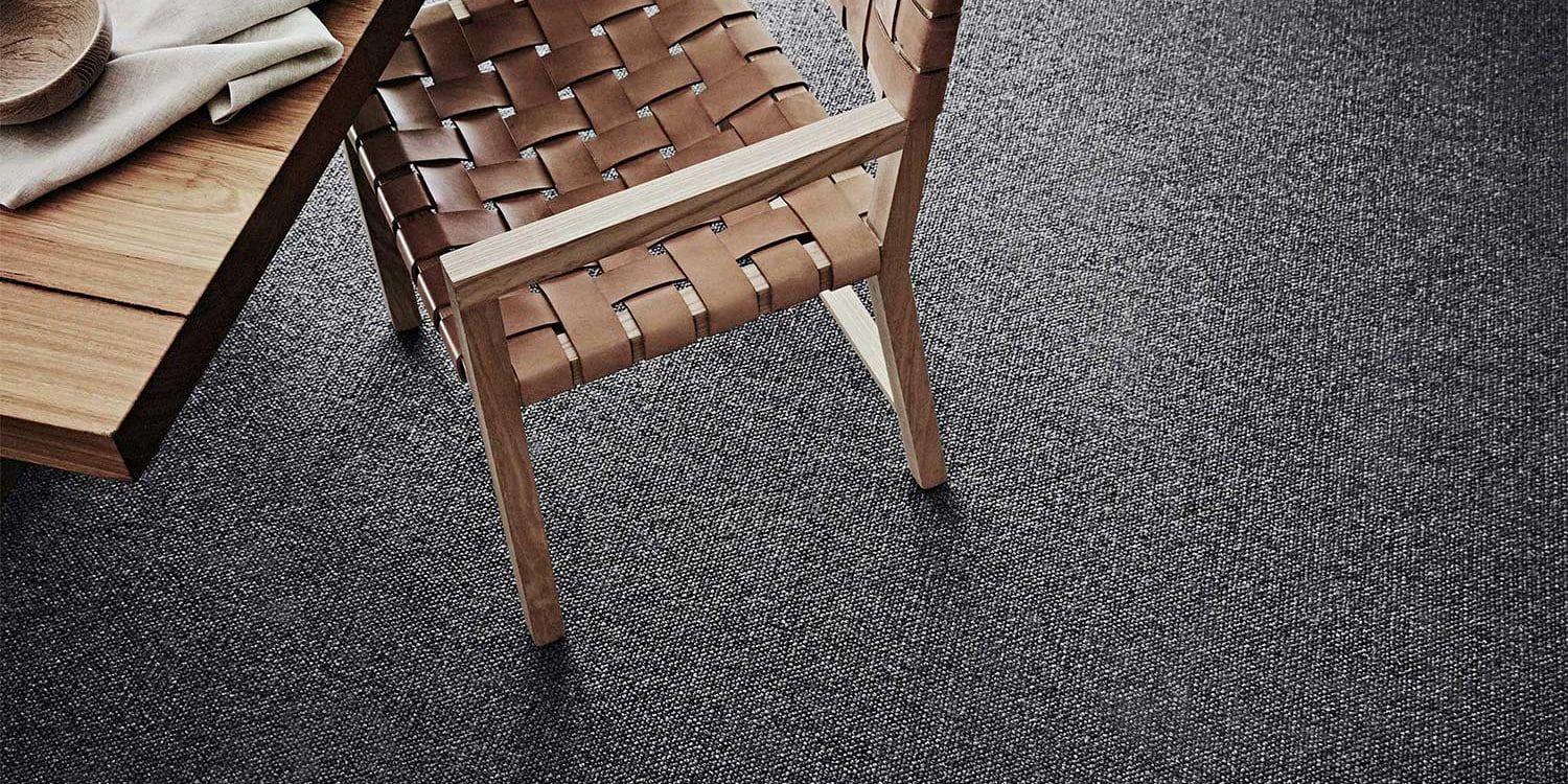 Wooden table and chair on a woven gray rug.
