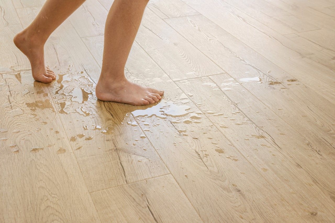 Bare feet walking on wet wooden floor. Water puddles visible.