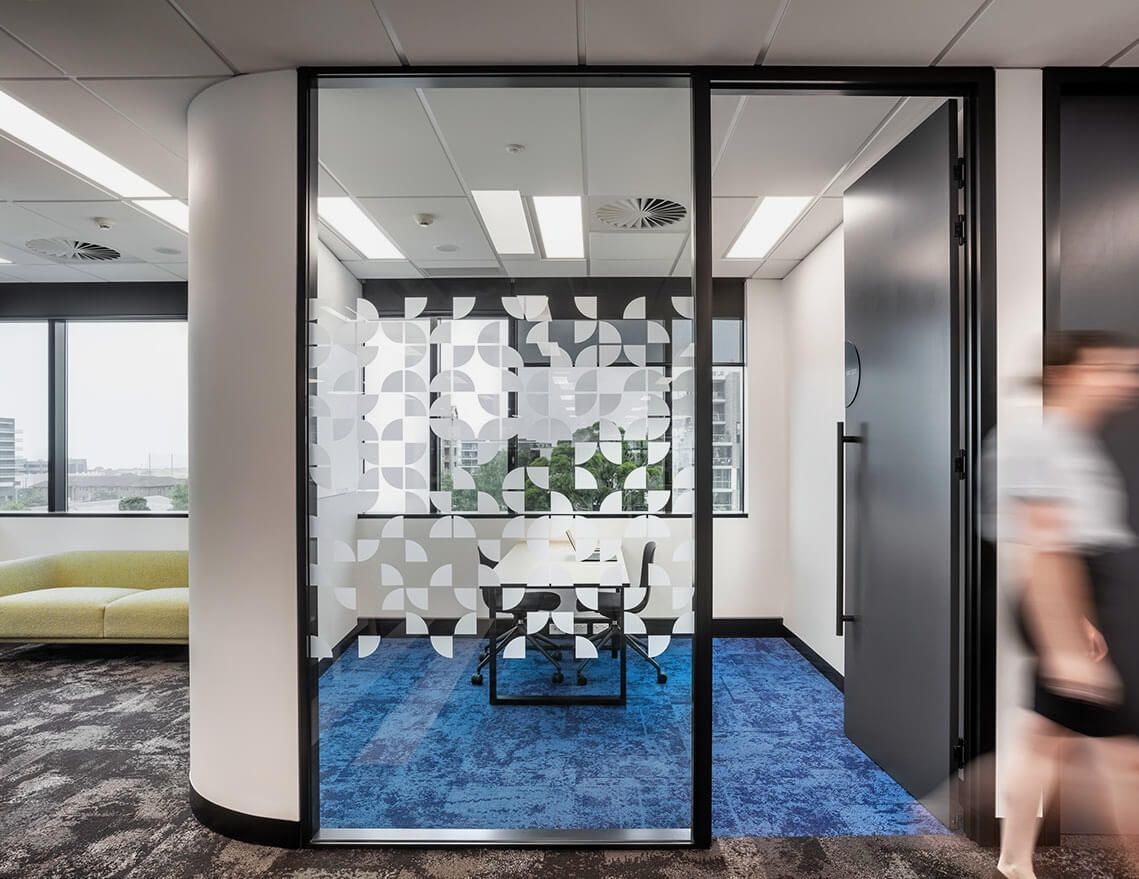 A Group of People Are Walking Through a Room with A Table and Chairs — Tony Di Milia Flooring in Unanderra, NSW
