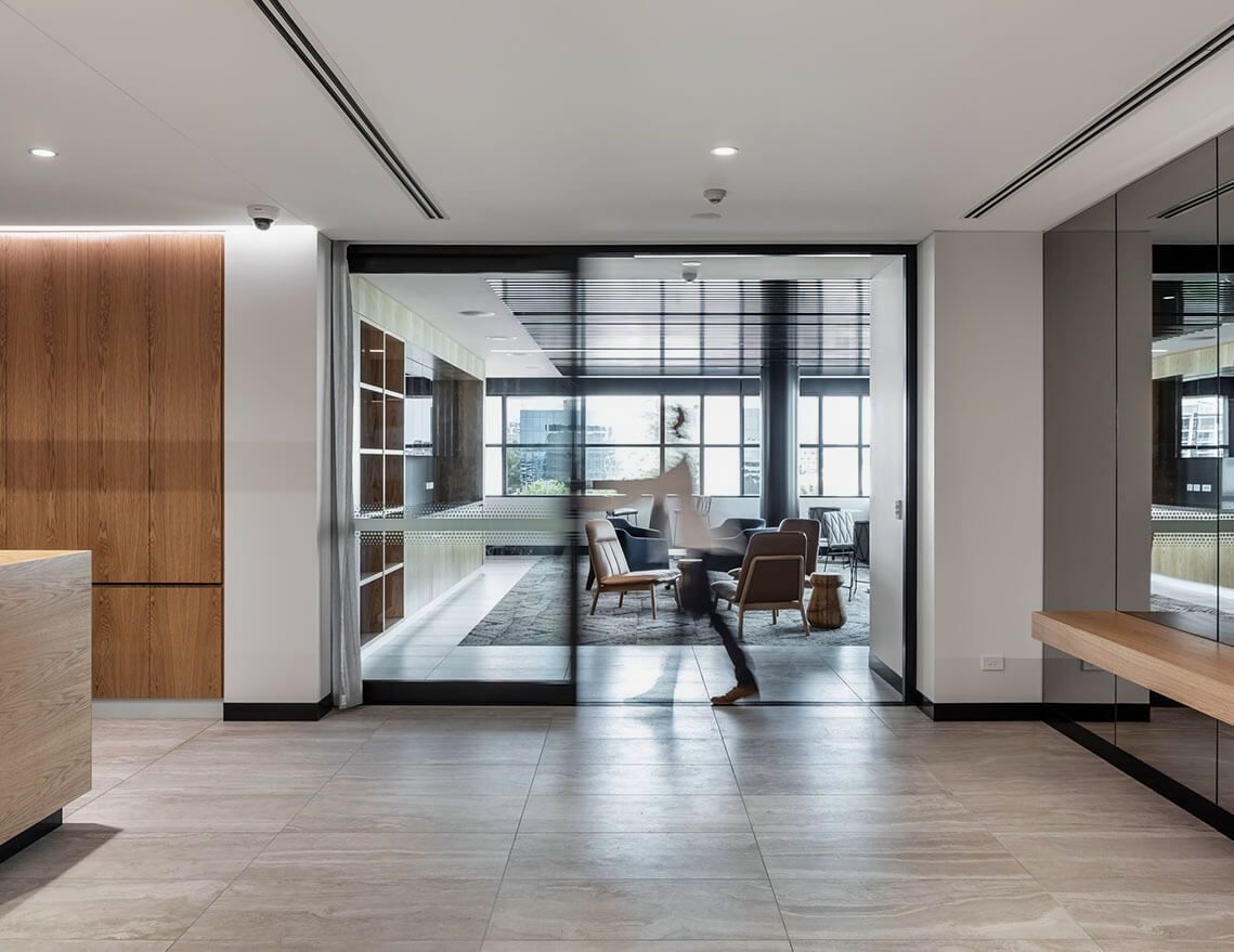 A Woman Is Walking Through a Large Room with Sliding Glass Doors — Tony Di Milia Flooring in Unanderra, NSW