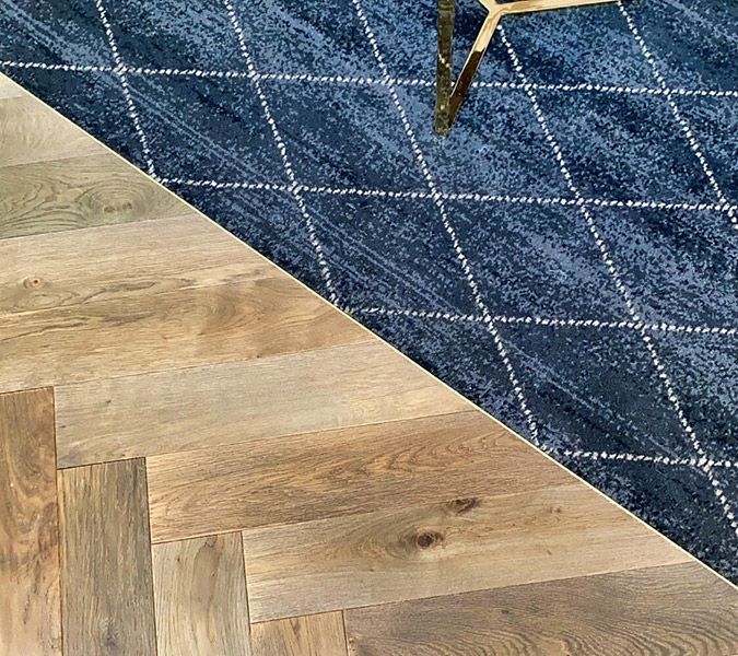A Wooden Floor Next to A Blue Rug and A Chair — Tony Di Milia Flooring in Unanderra, NSW