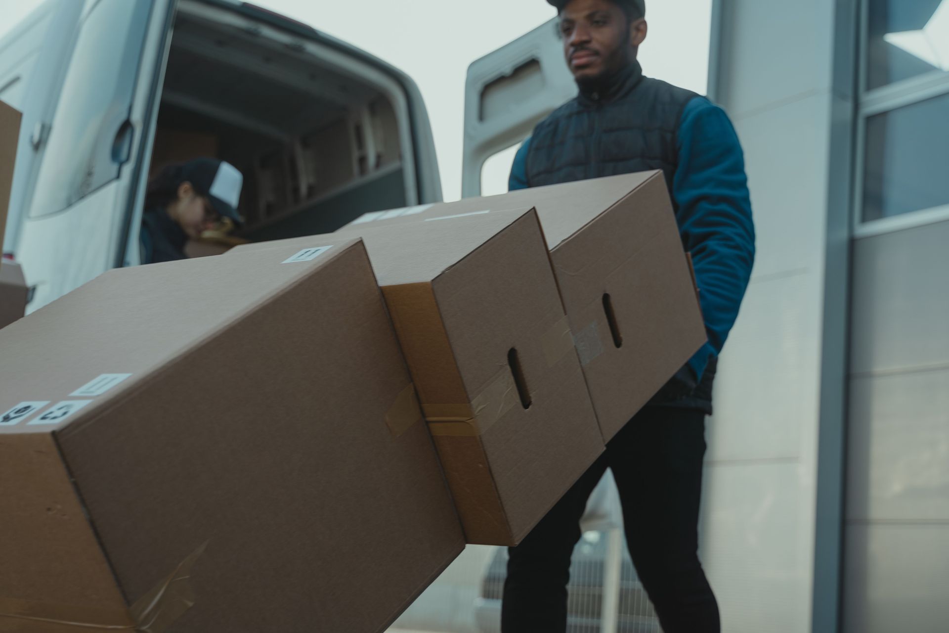 Professional mover carrying cardboard boxes from a truck, full-service packing by Renton Movers Pros.