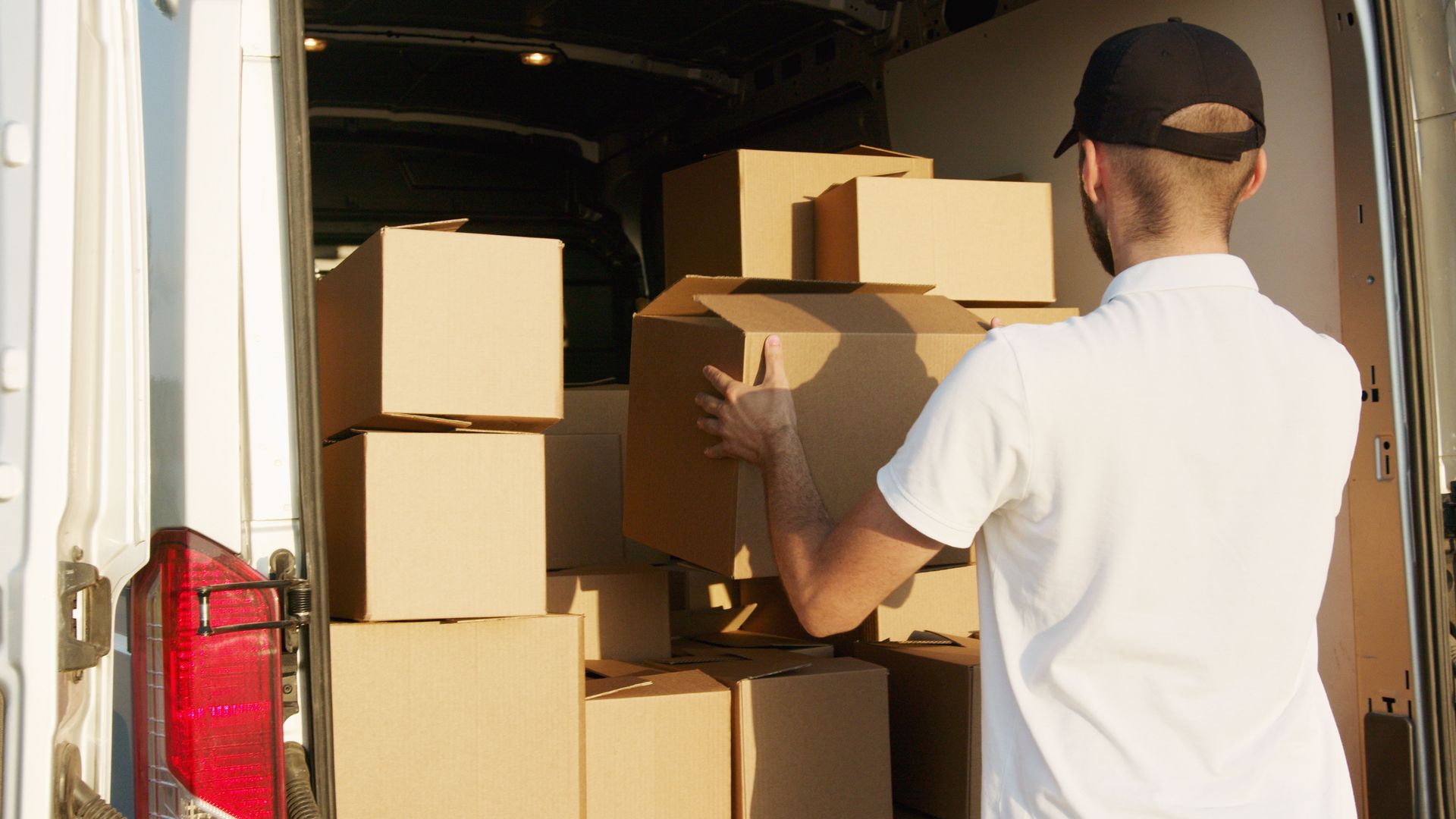 Mover loading cardboard boxes into a moving truck, loading and unloading services by Renton Movers Pros.