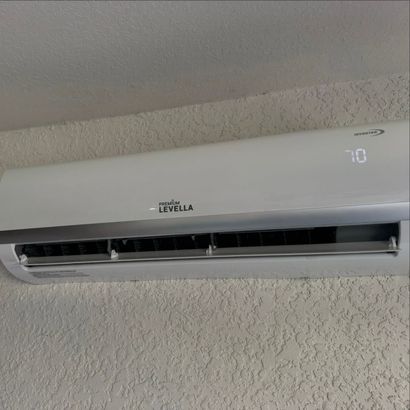 Wall-mounted white air conditioner on a light-colored wall, showing a digital temperature display.
