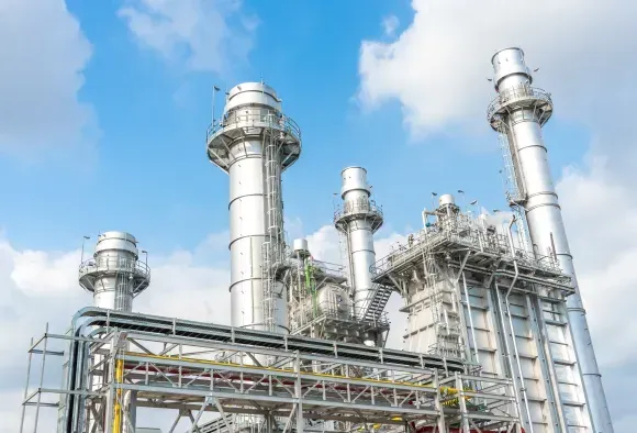 Large industrial facility with metal towers and pipelines, representing energy production and operations.