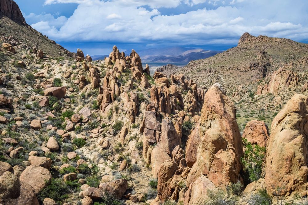 Rocky desert canyon with tall tan spires under a cloudy blue sky