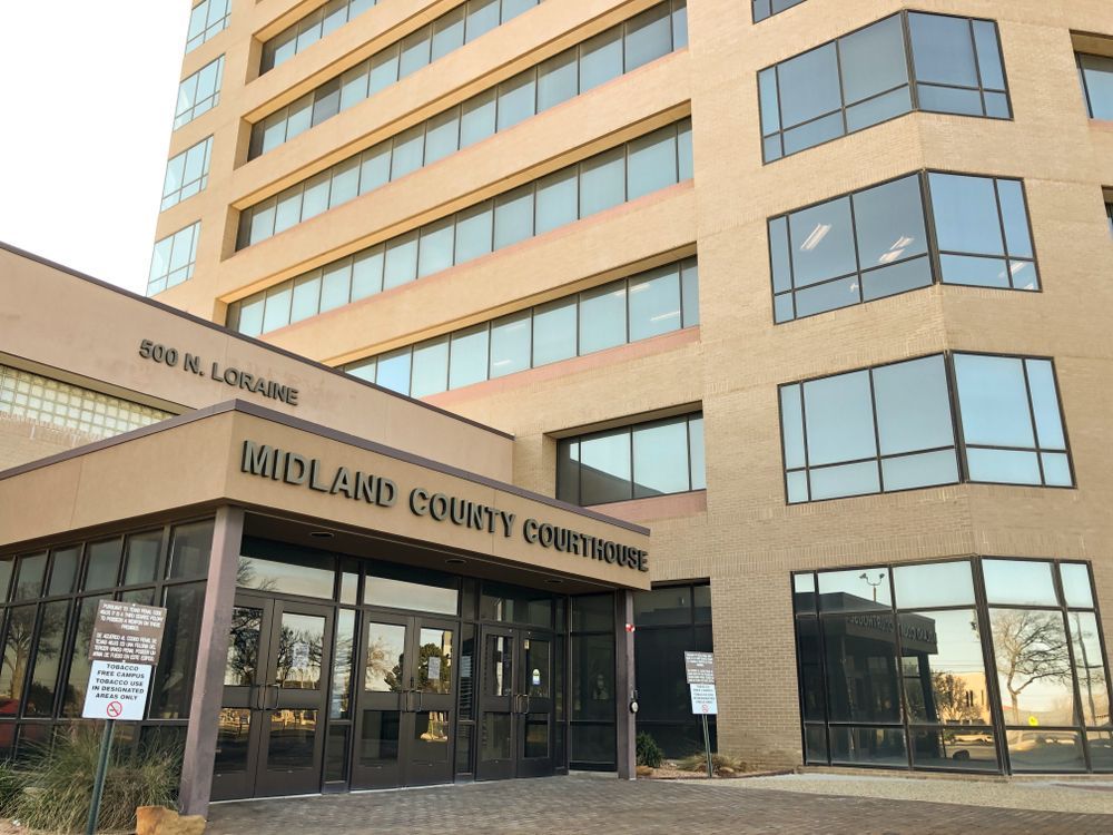 Midland County Courthouse entrance on a sunny day, with tan brick and glass windows