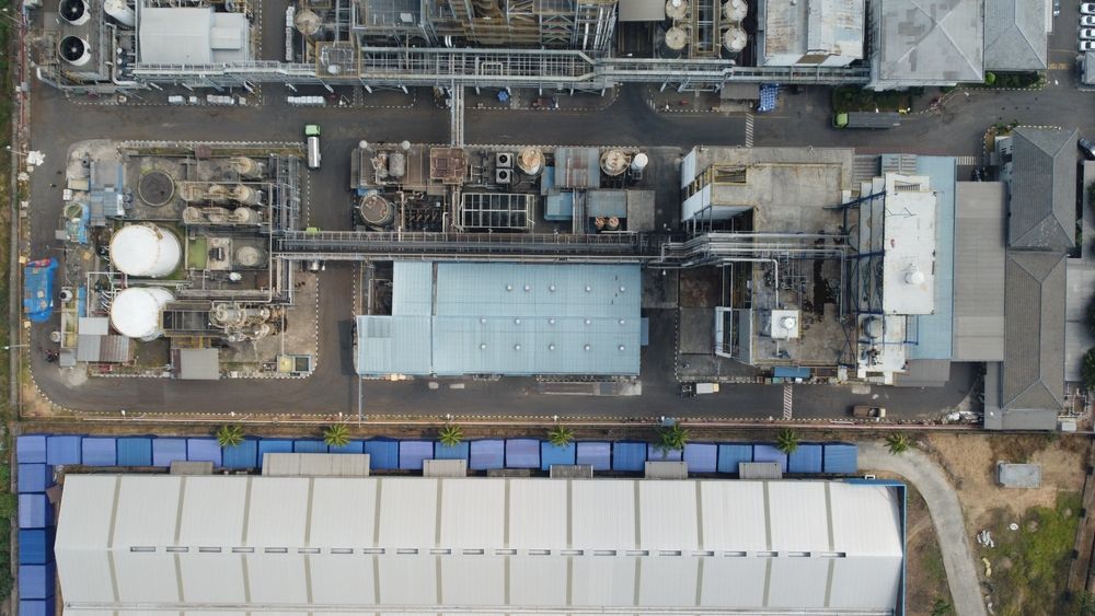 An aerial view of a large-scale industrial facility or factory. a complex network of metal pipes, tanks, and tall distillation columns, showcasing the intricate and functional design of the plant's