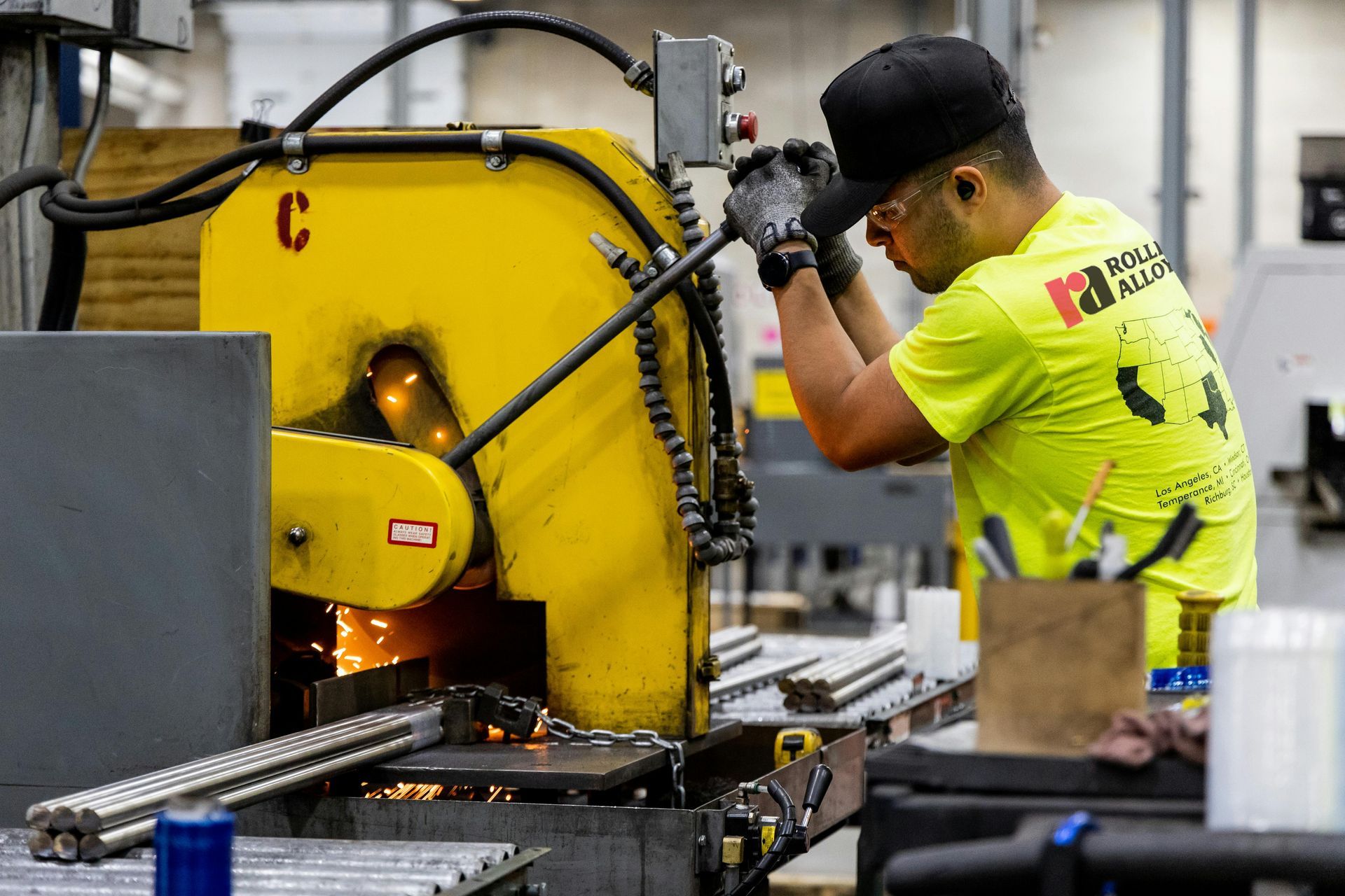 Factory worker operating industrial cutting equipment with sparks flying in a manufacturing facility.