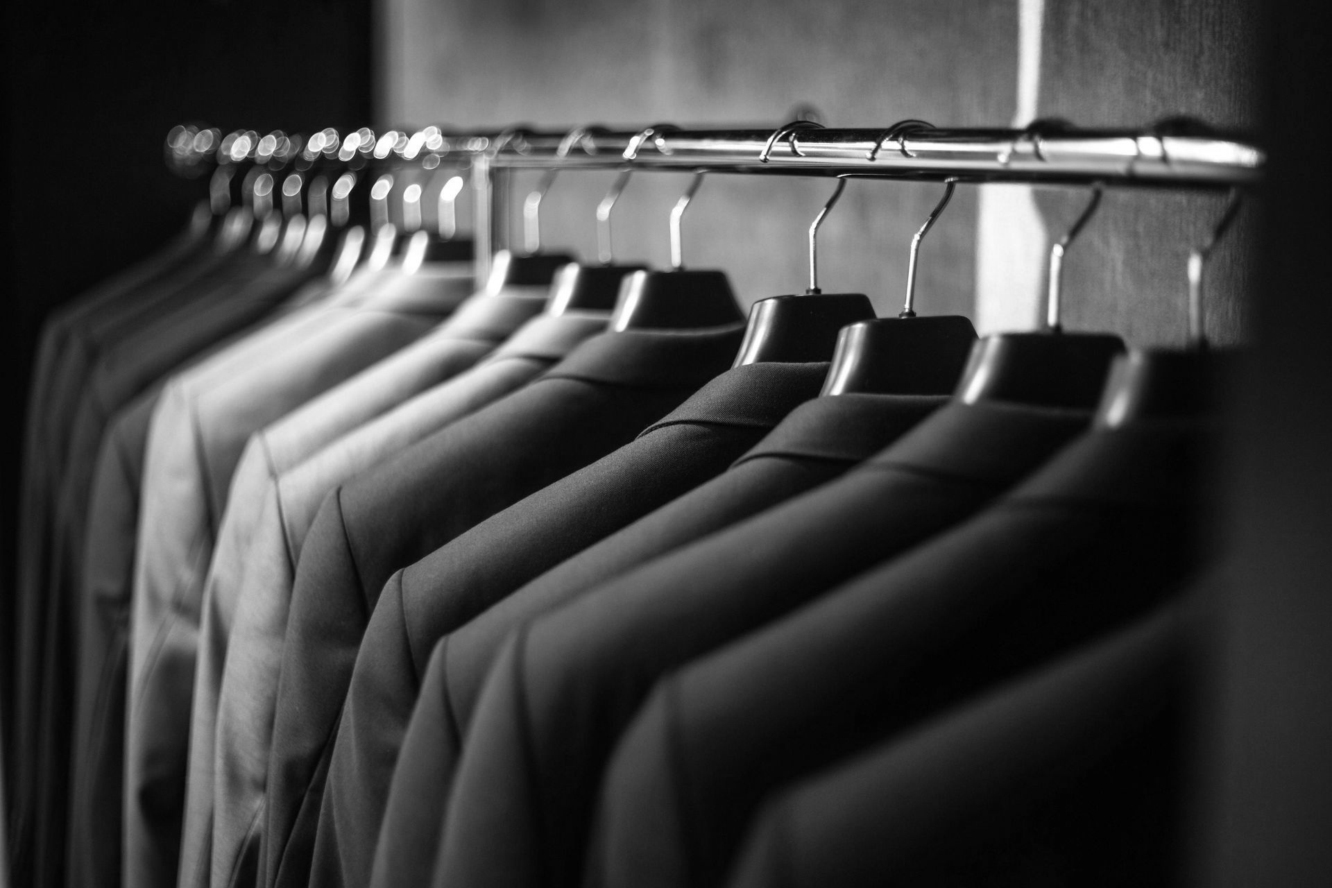 Row of suits on hangers in a wardrobe, representing professional attire and business formal wear.