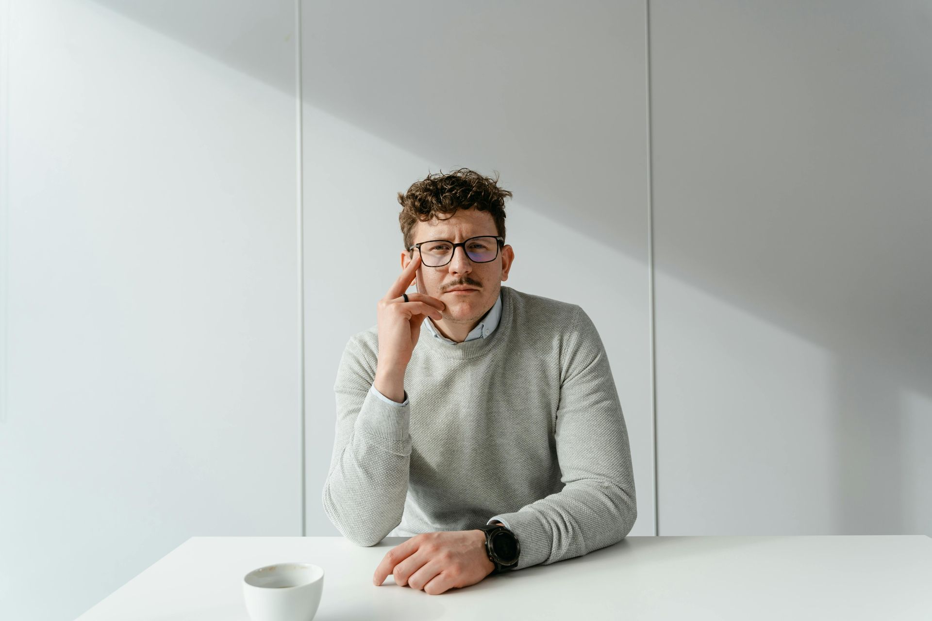Business professional thinking at a desk with coffee cup, representing tax strategy and compliance review.