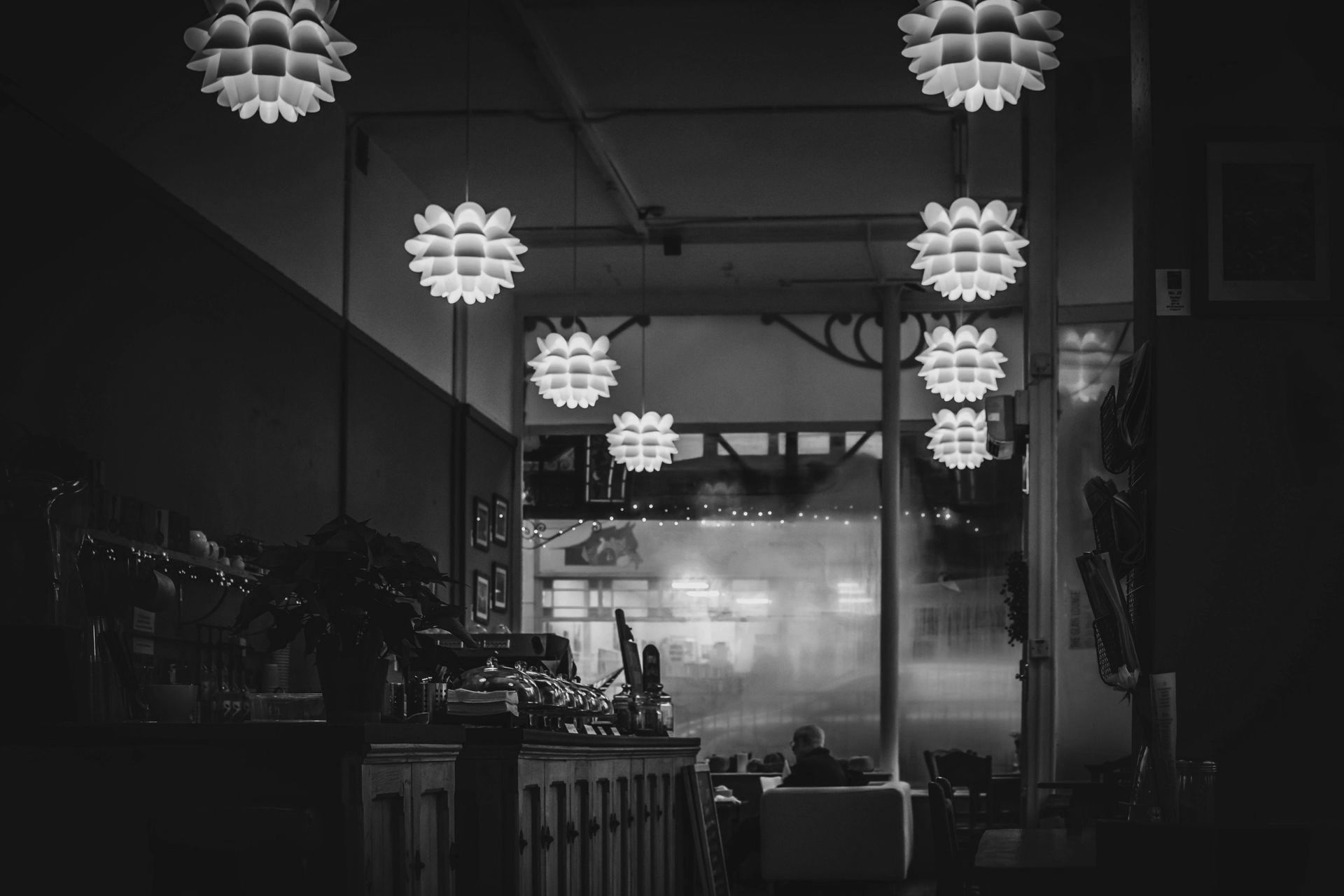 Dimly lit café interior with hanging lights and seating, creating a relaxed restaurant atmosphere.