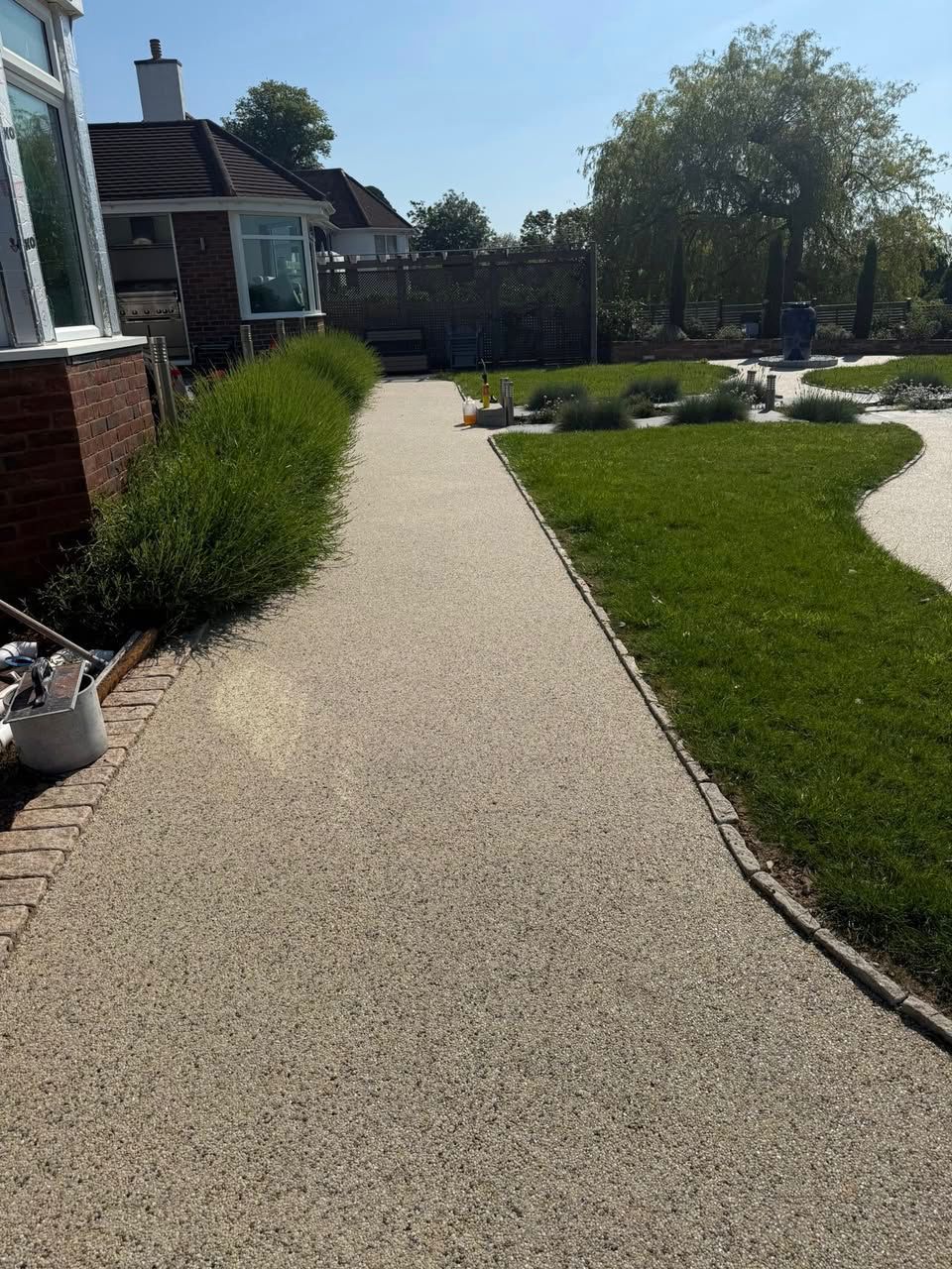 Gravel walkway beside a house and trimmed lawn on a sunny day