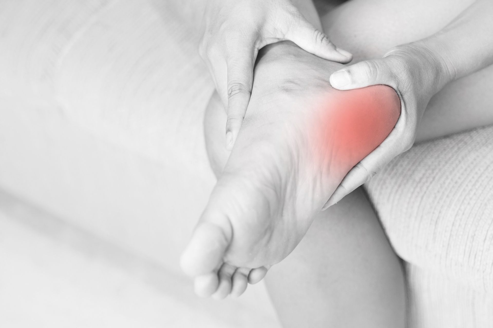 Foot with red highlighted heel being held, indicating pain.