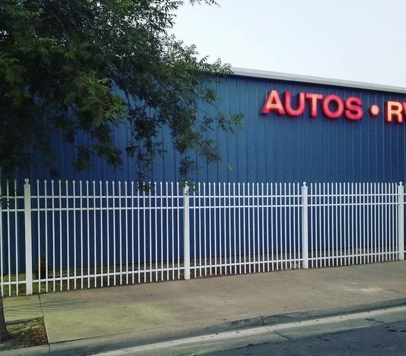 White metal fence in front of a blue building with red 