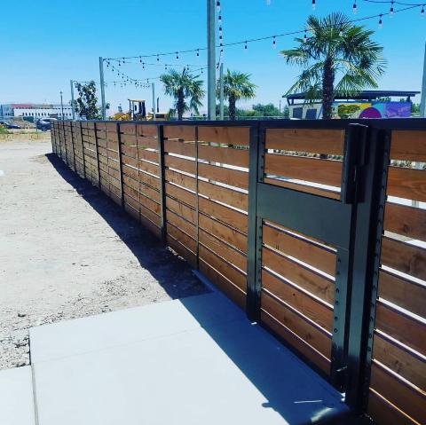 Wooden slat fence with a gate in a sunny outdoor setting.