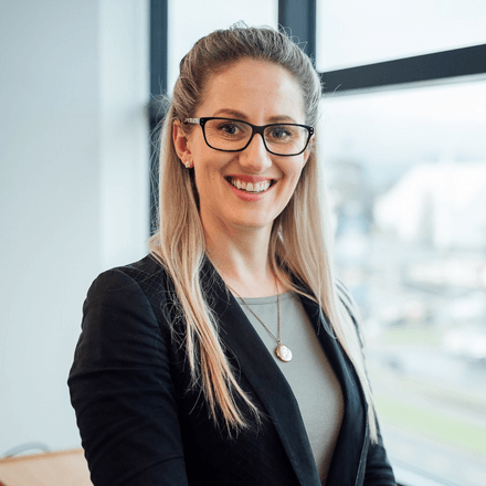 Chelsea Lucking wearing glasses and a black jacket is smiling for the camera .