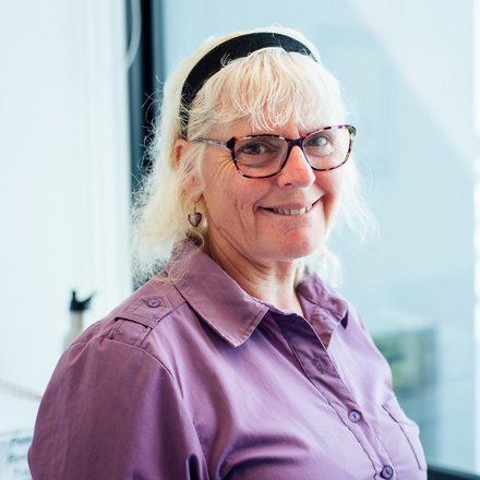 Keren Thompson wearing glasses and a headband is smiling for the camera