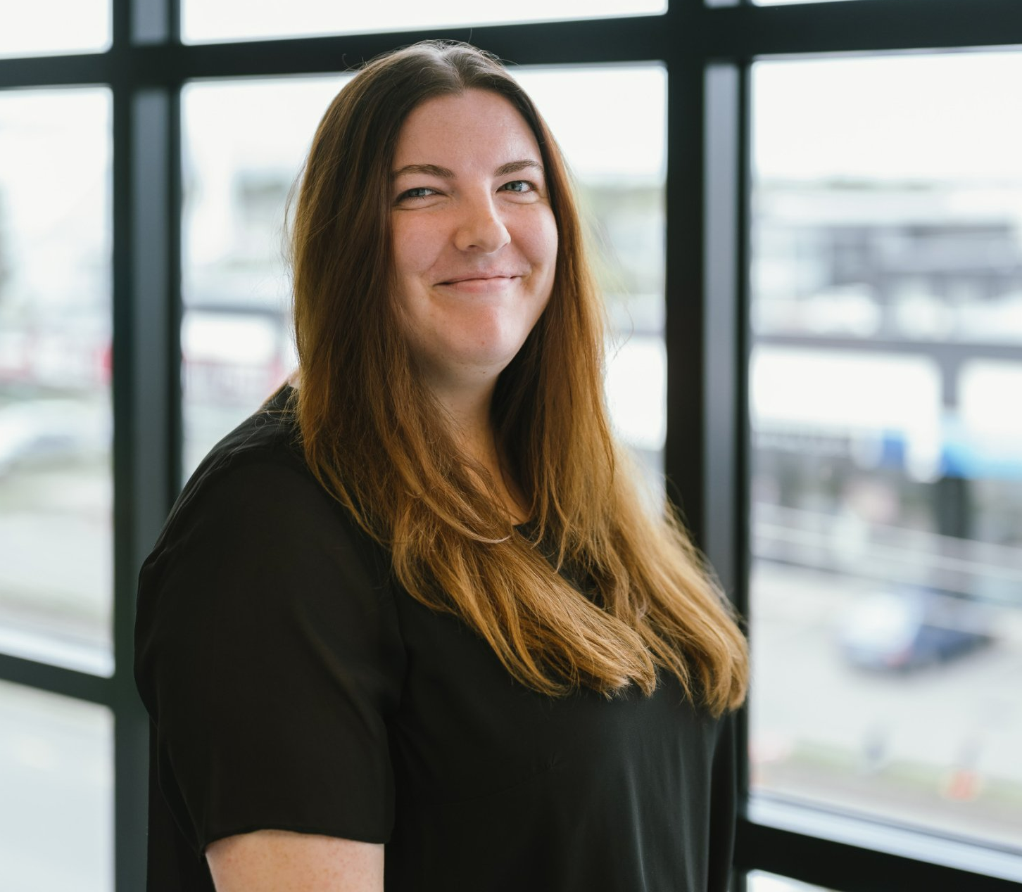 Laura Mantell in a black shirt is smiling in front of a window .