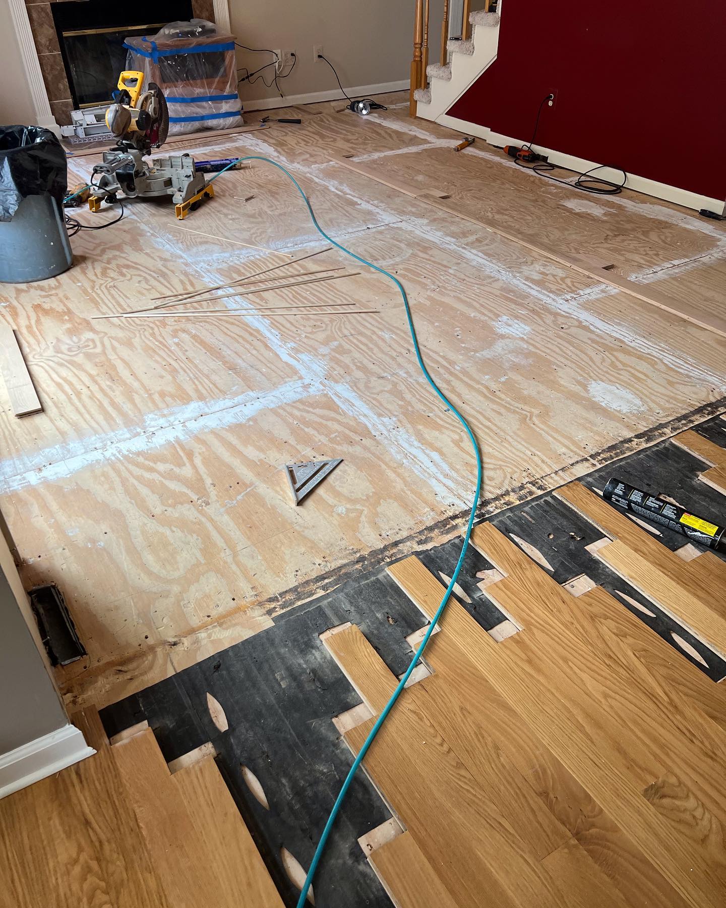 A wooden floor is being installed in a living room.