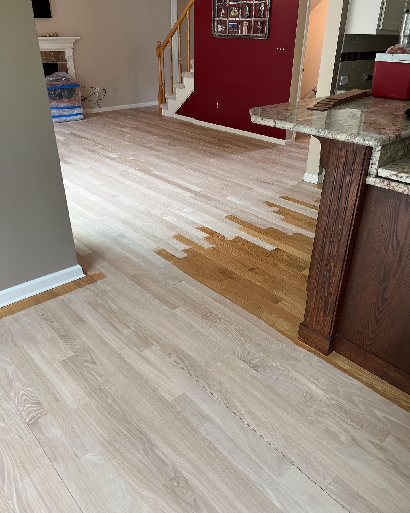 A kitchen with a wooden floor and a red wall.