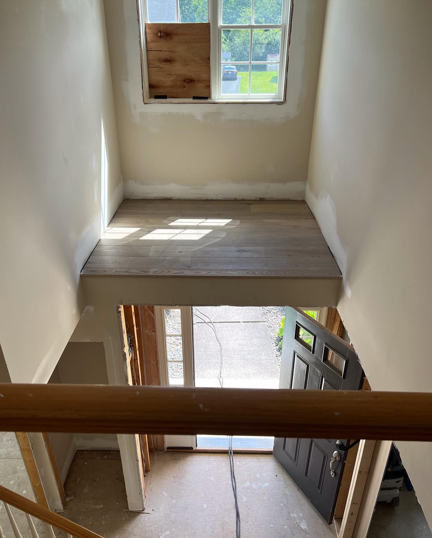 A staircase with a wooden railing leading to a door and a window.