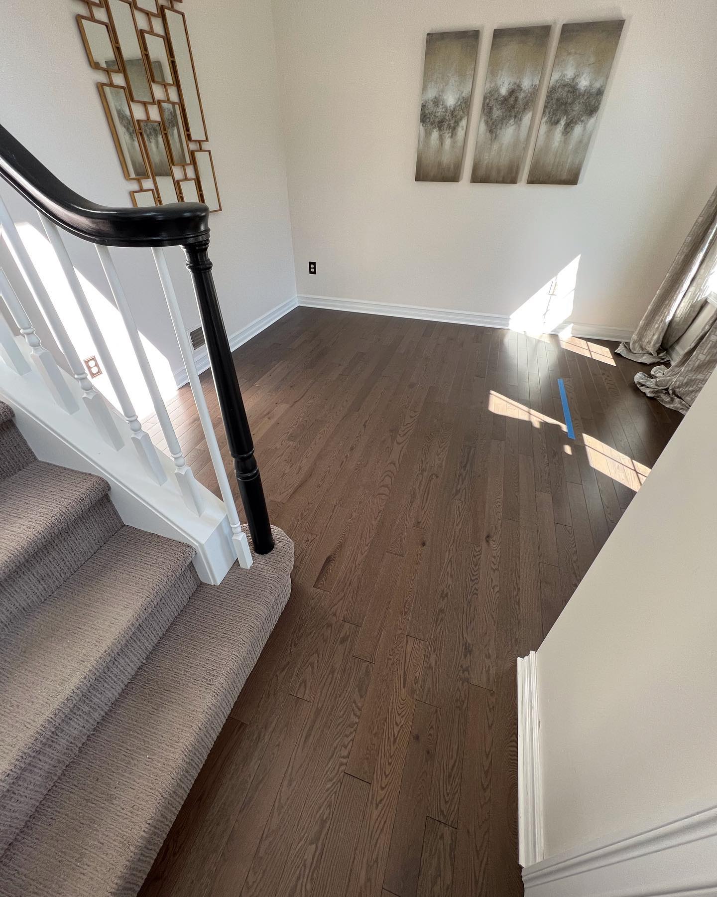 There is a staircase in the middle of the room with a wooden floor.