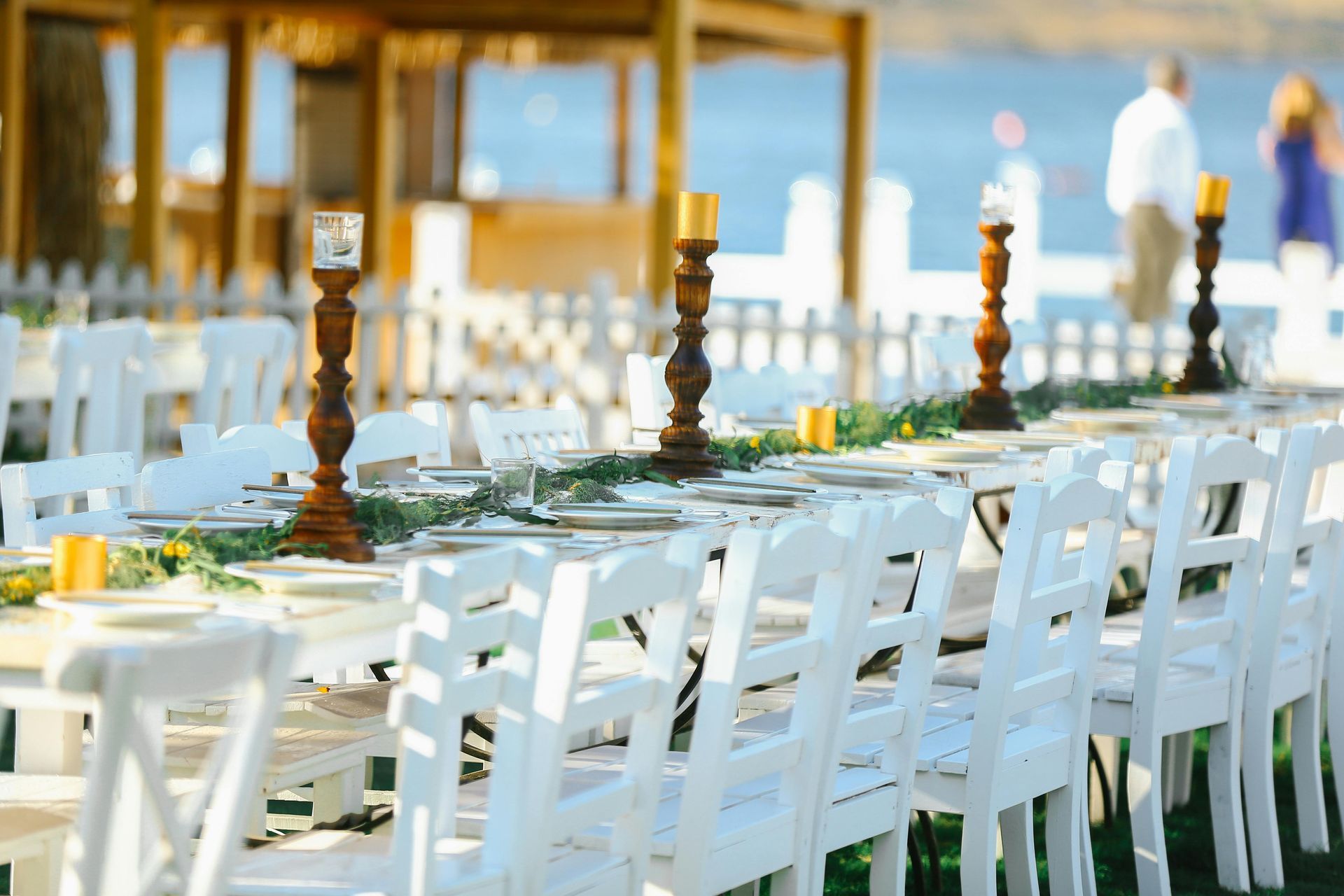 White chairs and set tables arranged outdoors for a formal waterfront event