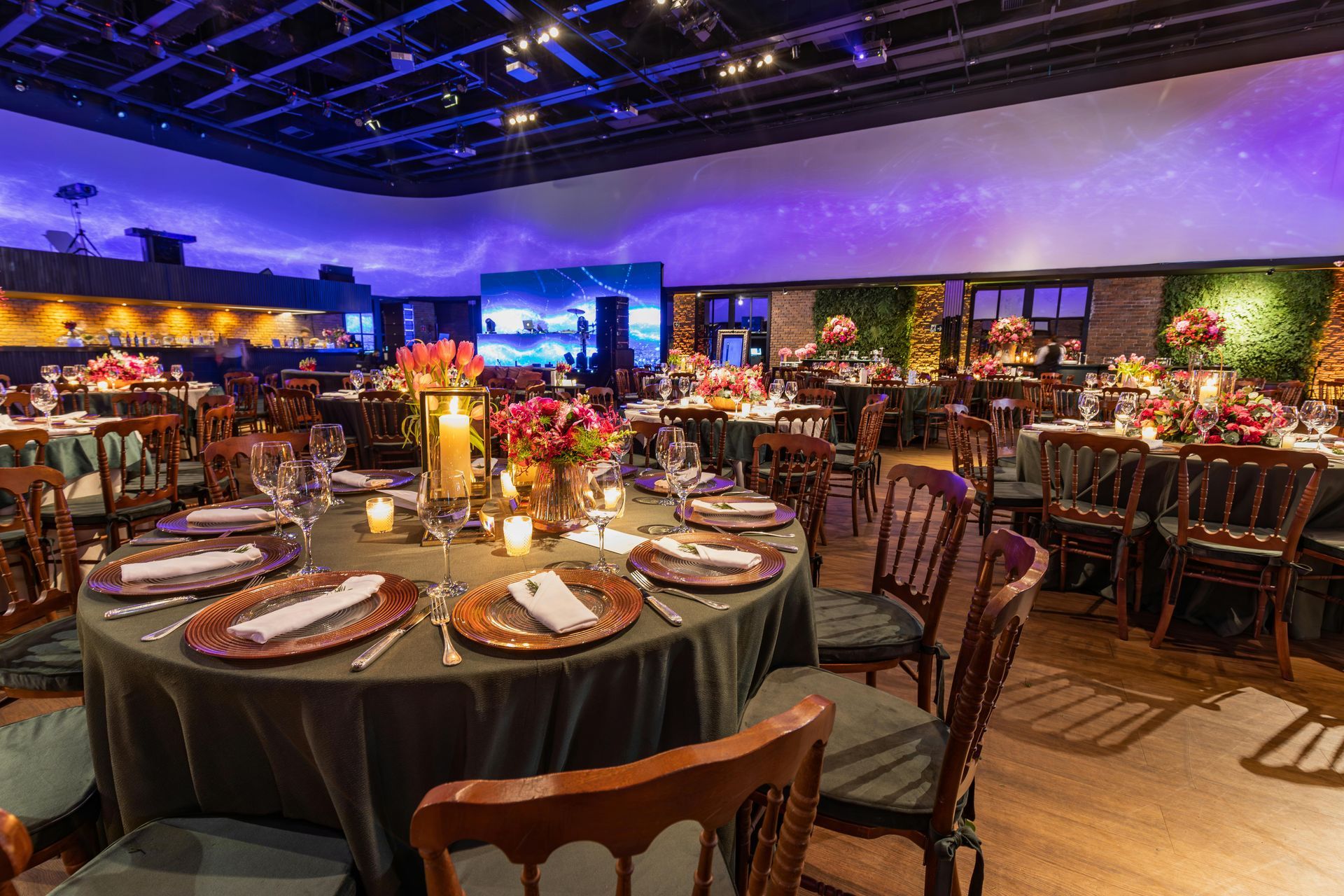 Elegant banquet hall with round tables, candlelight, and purple-blue ambient lighting set for an event