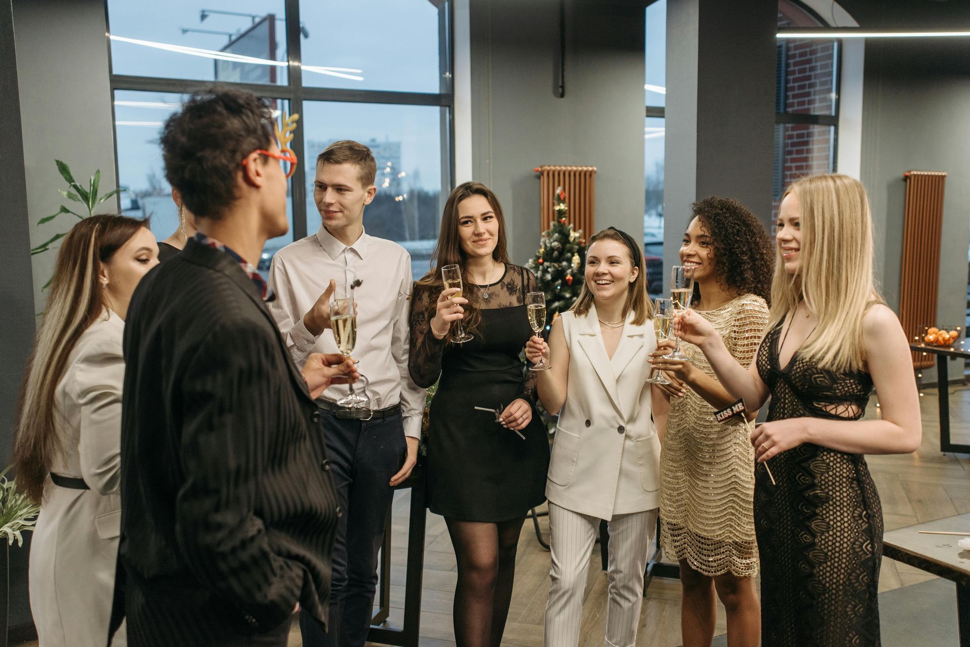People in formal attire chatting with drinks in a modern office lobby