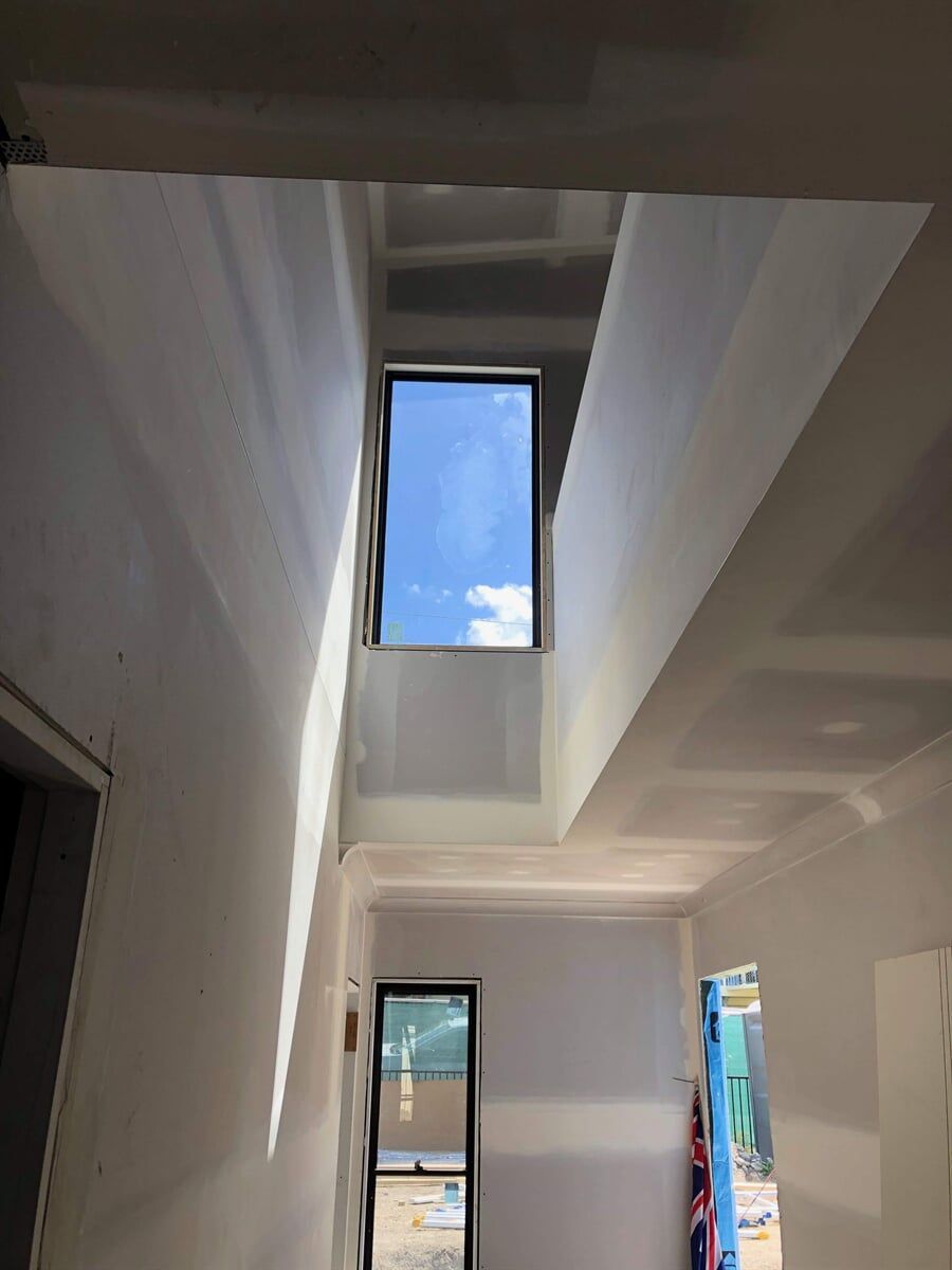 A Hallway With a Staircase and a Window With a Blue Sky in The Background  — Plaster Installation in Bensville, NSW