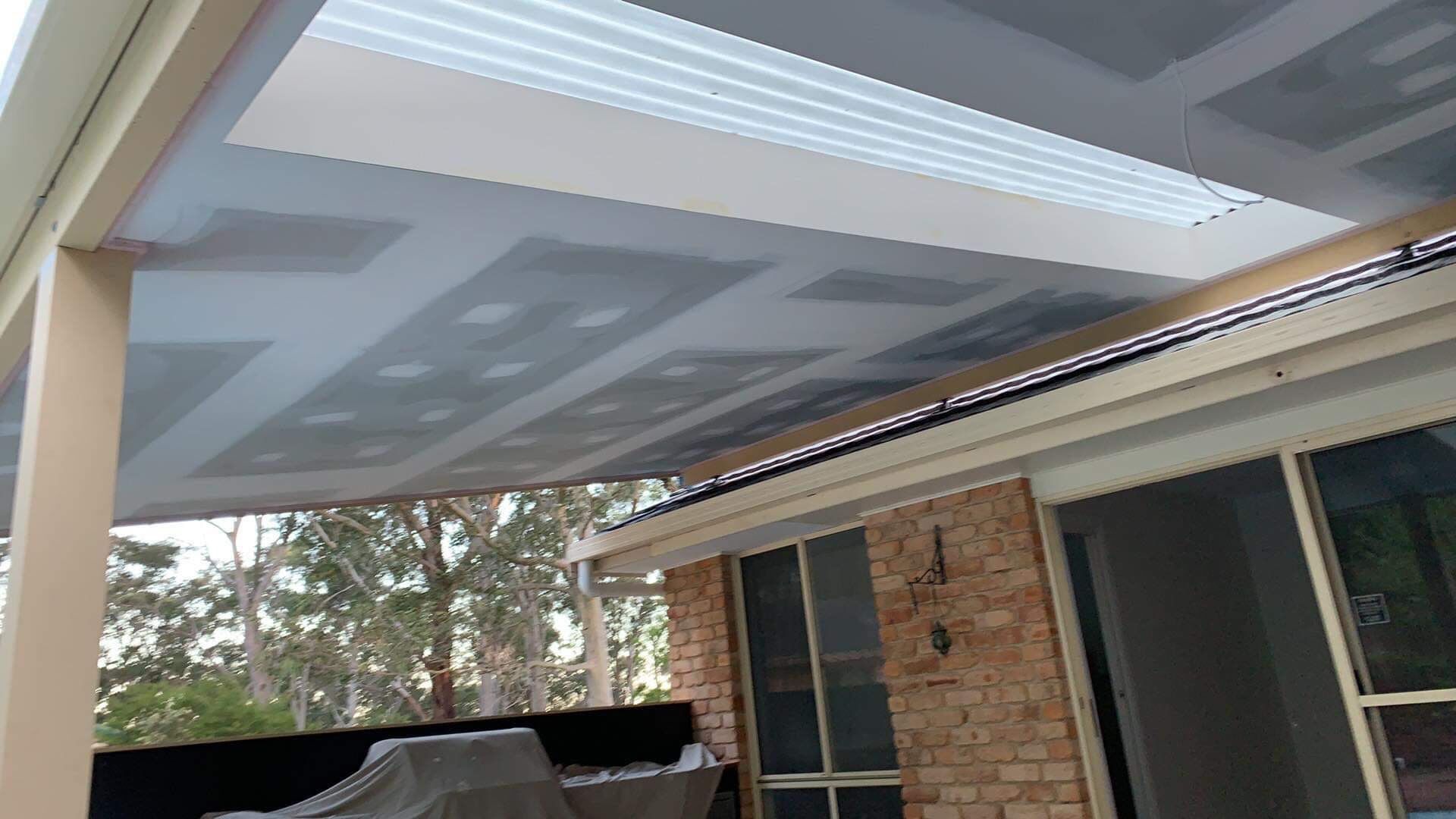 A Brick House With a Covered Patio and a Grill — Plaster Installation in Bensville, NSW