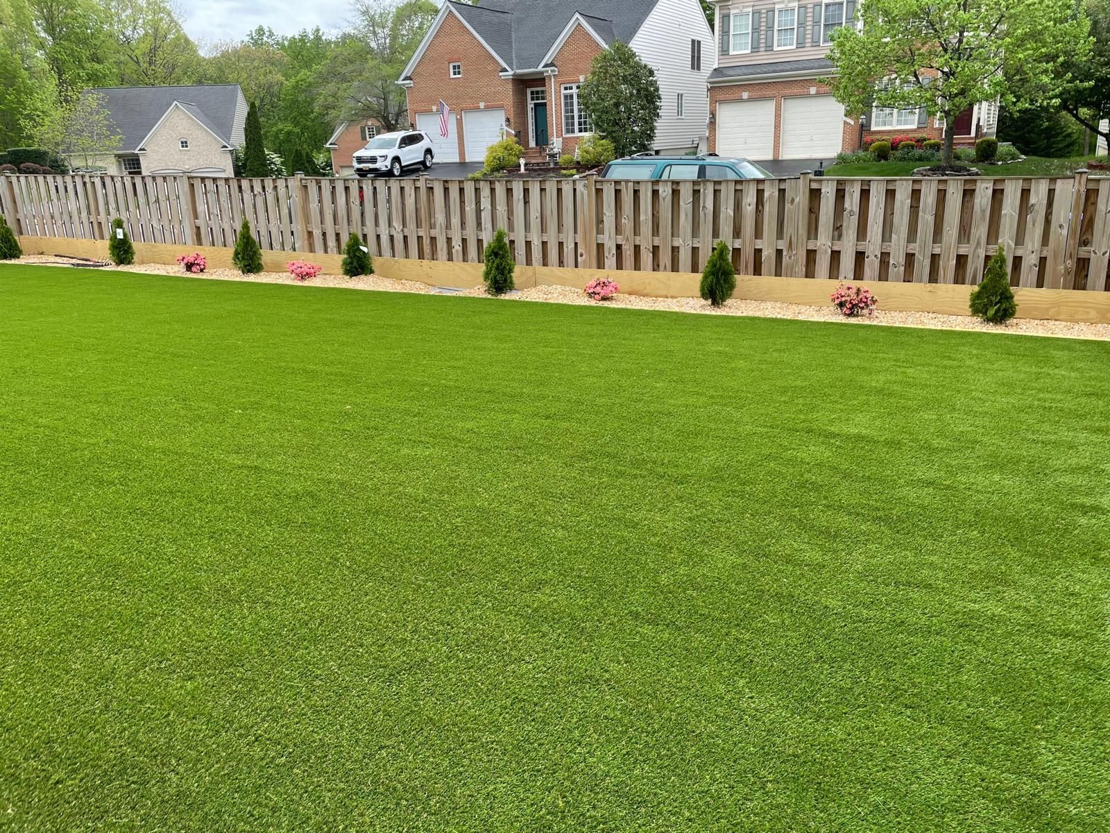 Freshly mowed lawn with a new fence and small shrubs in a suburban backyard.