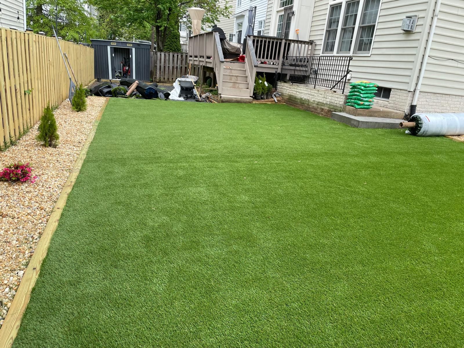 Backyard with new green lawn, gravel border, and a house deck in the background