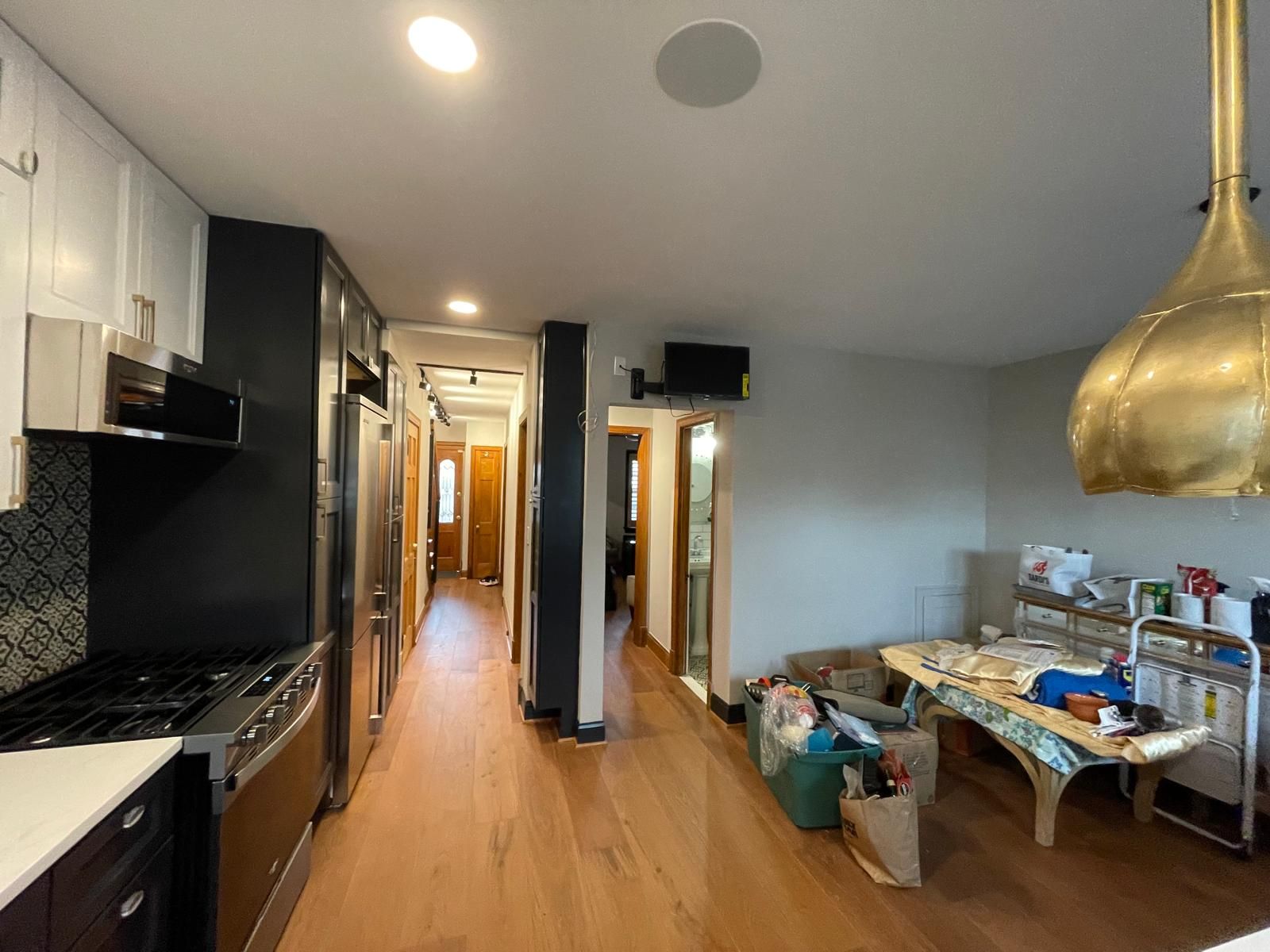 Modern kitchen and dining area with black cabinets, wooden floor, and a cluttered table under pendant light
