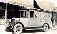 Vintage black-and-white delivery truck parked beside a building