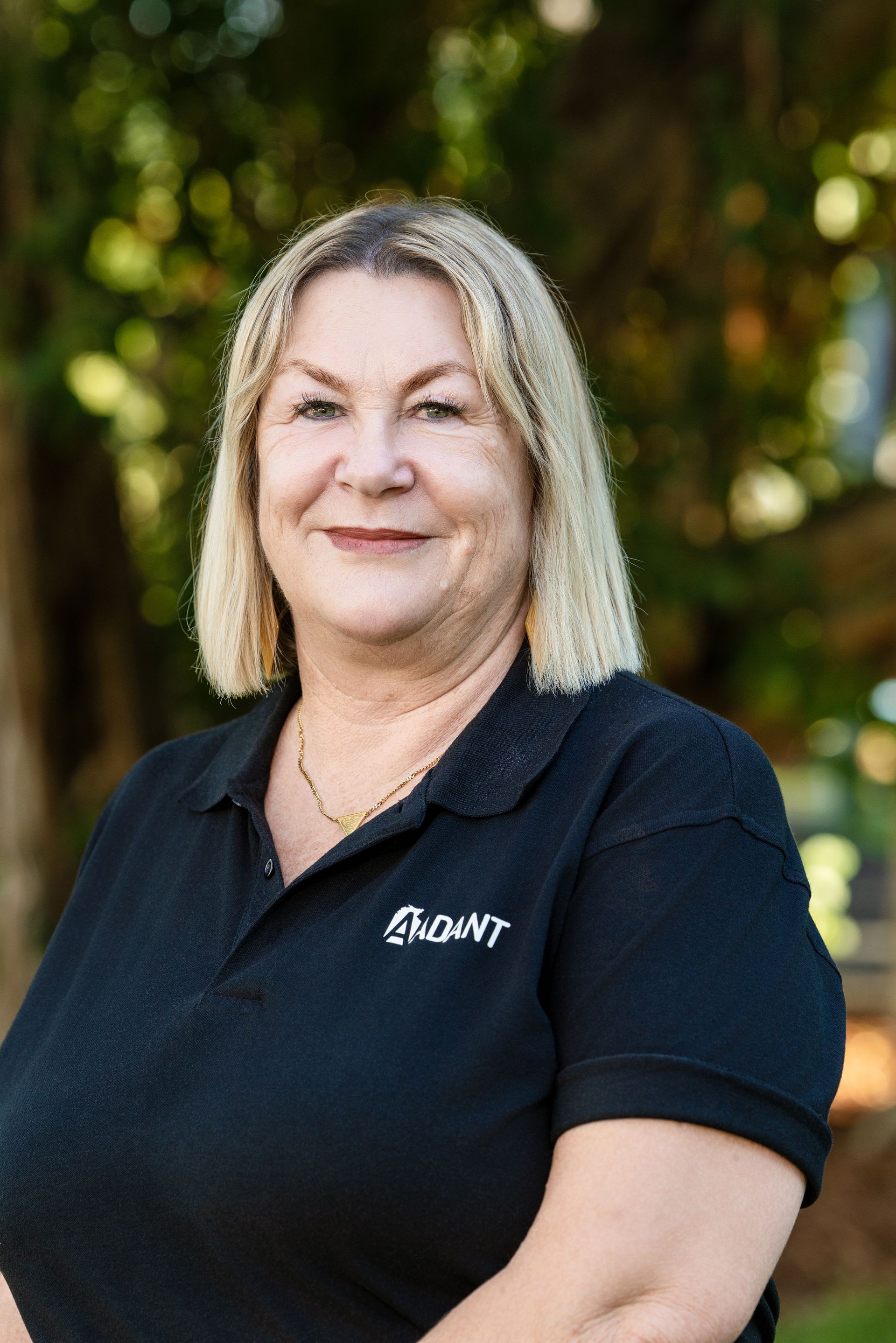A person with blonde hair and bangs, wearing a brown and black leopard-print top, smiles slightly at the camera.